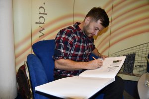 Na zdjęciu Jakub Małecki podpisuje suę w kronice.